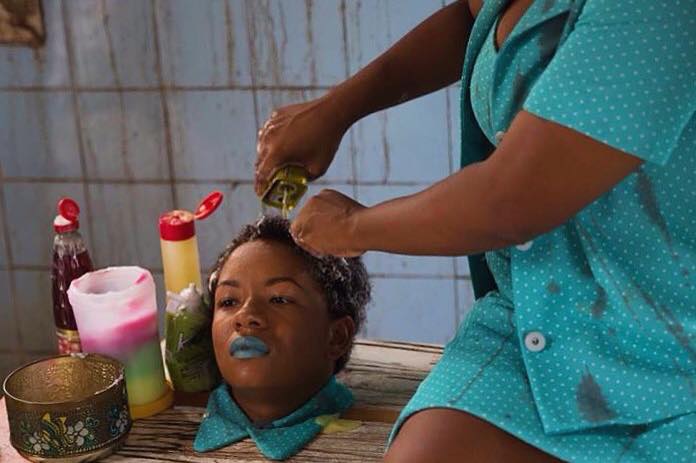 Kitchen Table Products - Kbela is a visual poem with very little dialogue. In this scene, a woman adds numerous kitchen products to a young woman's hair.
